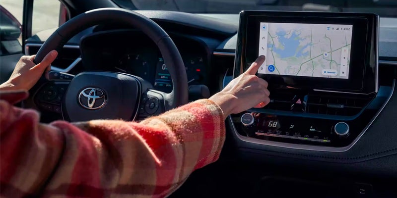 Woman driving 2024 Toyota Corolla in Roseville, CA, using navigation system